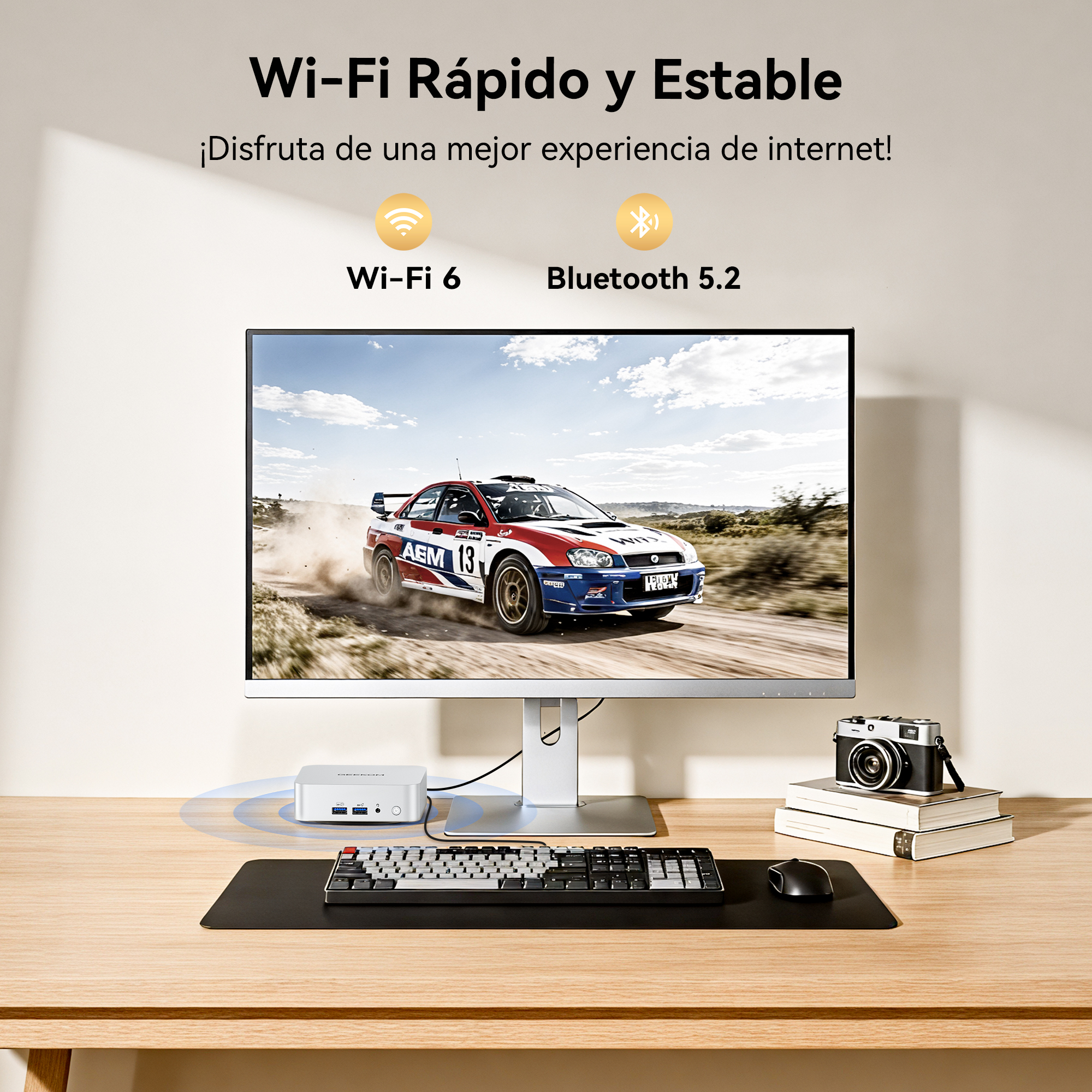 Un escritorio con computadora, teclado, mouse, cámara y un coche de rally en pantalla.