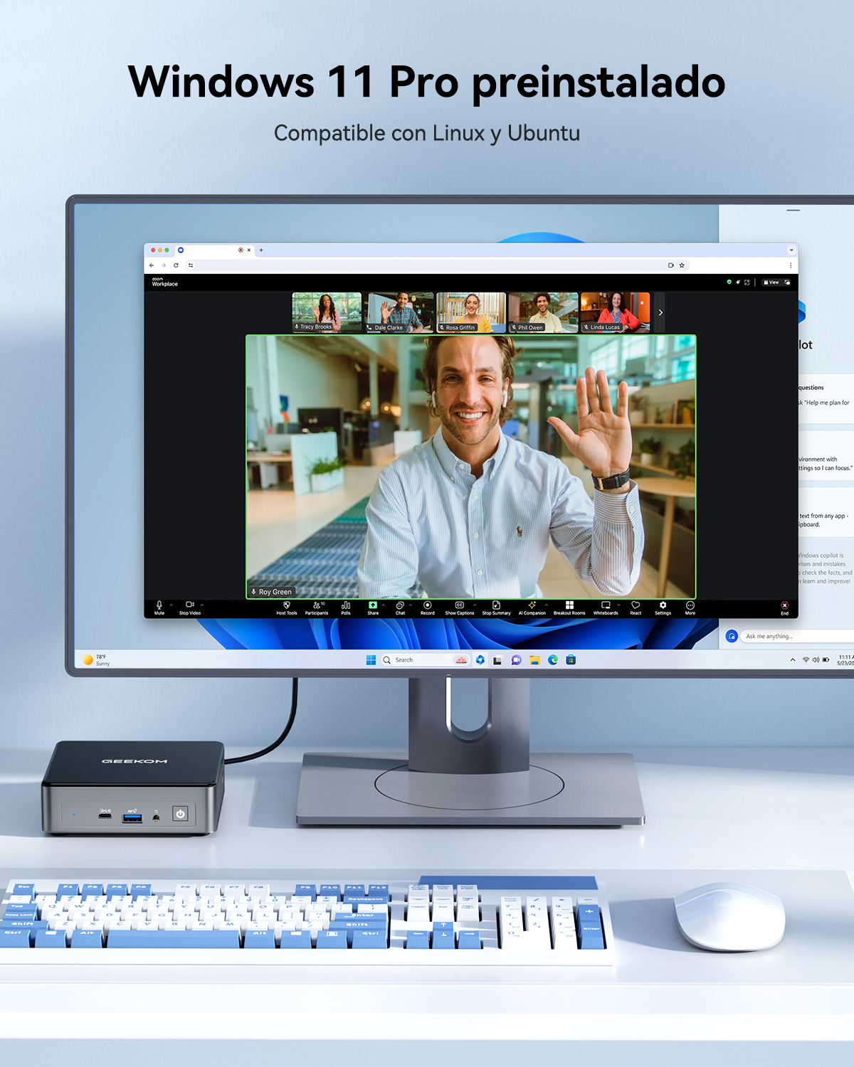 Un hombre saluda en una videoconferencia, se ven un PC, teclado y ratón.
