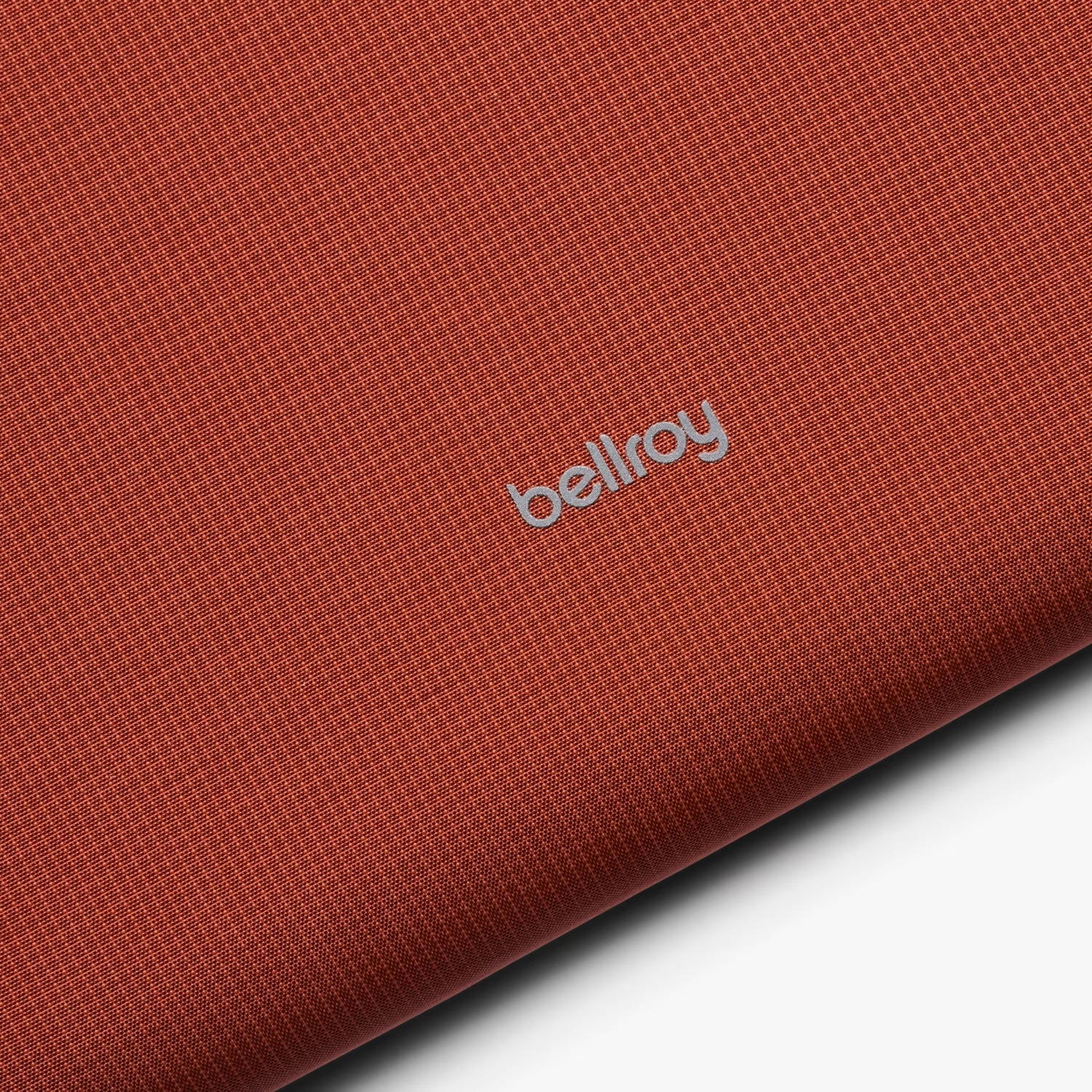 Tessuto rosso con logo Bellroy argentato. Primo piano.