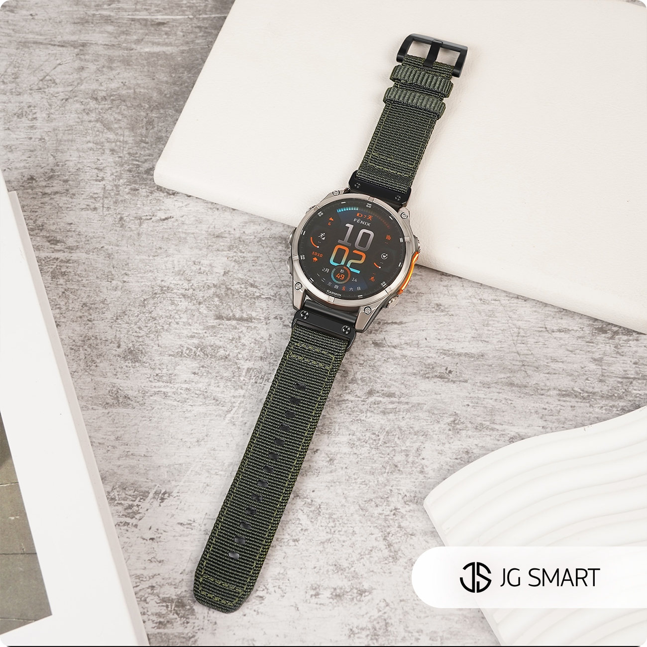 Zielony smartwatch z srebrną kopertą spoczywa na szarej powierzchni.