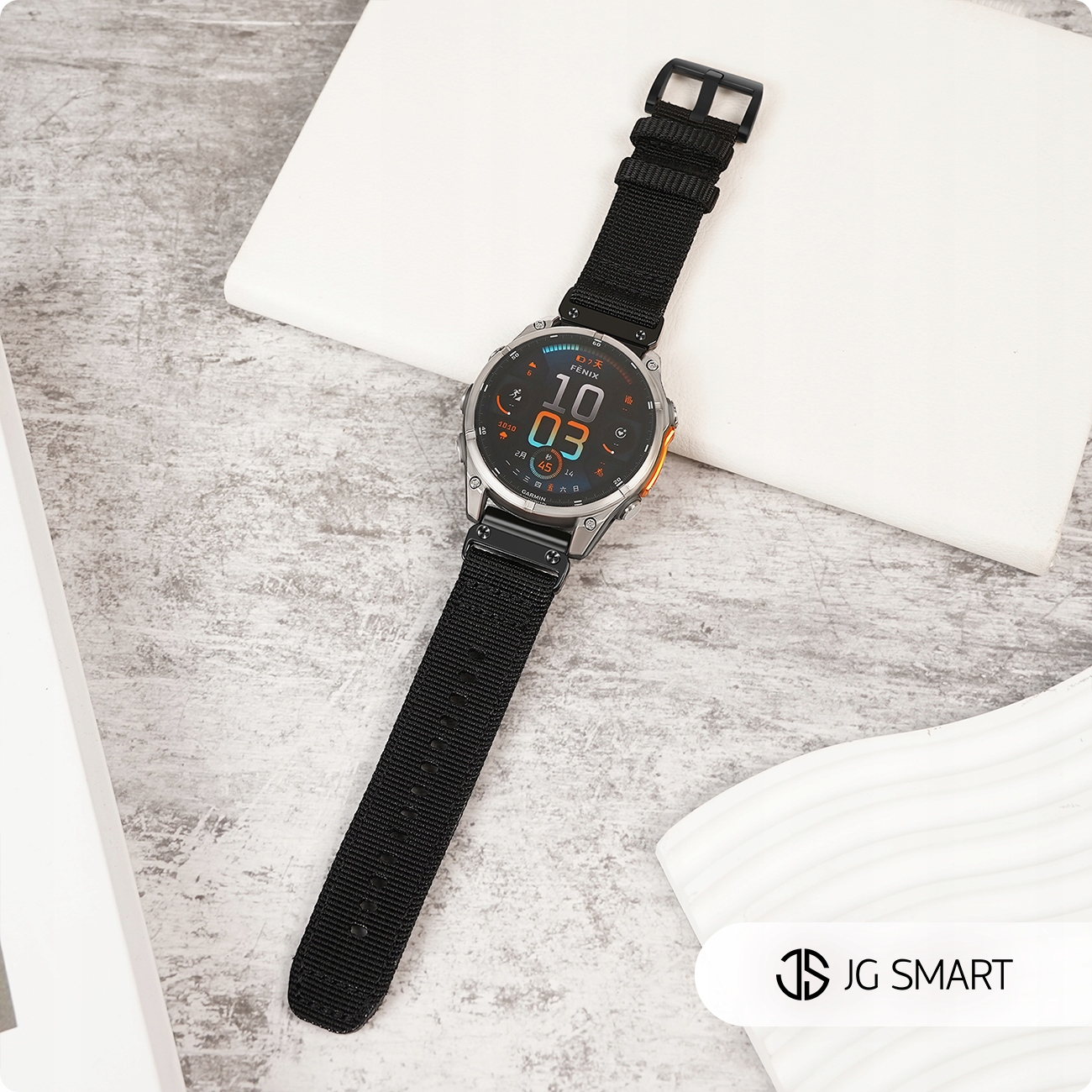 Srebrny smartwatch z czarnym paskiem leży na szarej powierzchni.