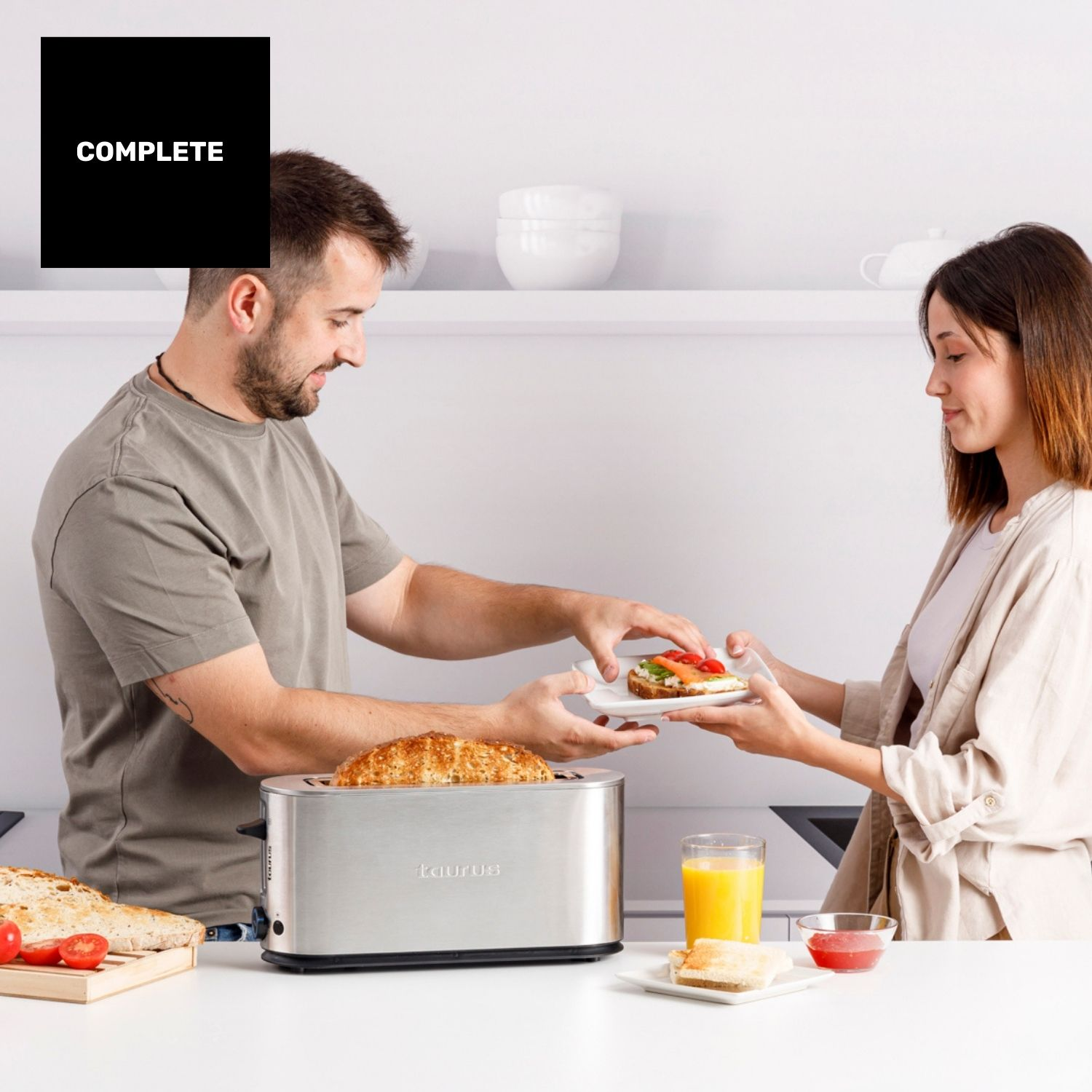 Pareja preparando desayuno en cocina moderna. Hombre da tostada a mujer con sándwich.