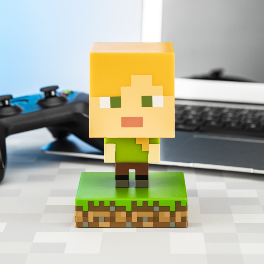 Figurka Minecraft Alex stoi na bloku trawy obok kontrolera.