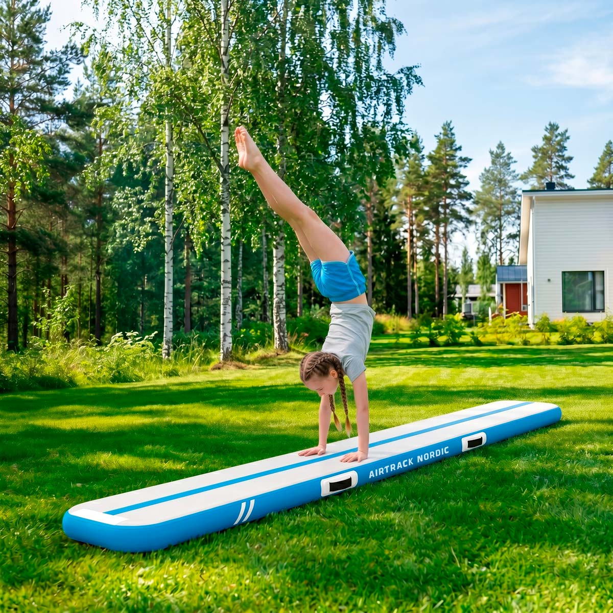 Dziewczynka robi stanie na rękach na nadmuchiwanej macie airtrack w ogrodzie.