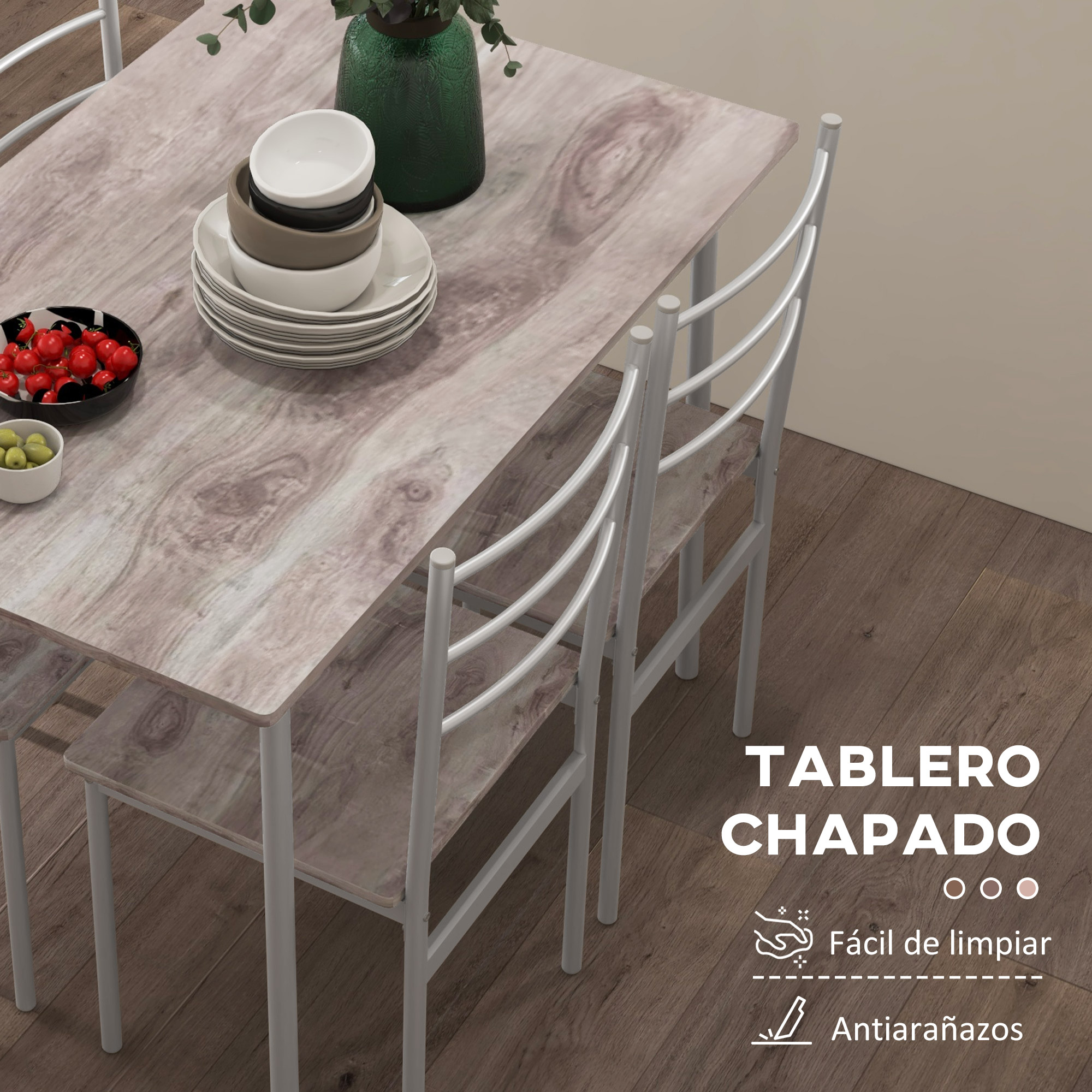 Mesa de madera veteada con sillas blancas, cuencos, fruta y jarrón verde.