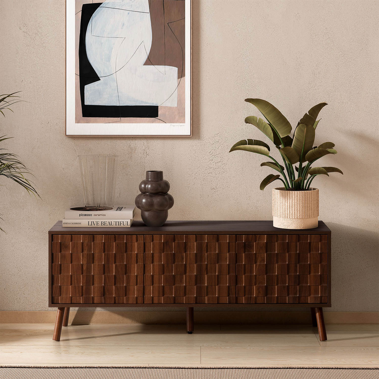 Un aparador de madera oscura con patrón geométrico. Encima: un libro, un jarrón y una planta.