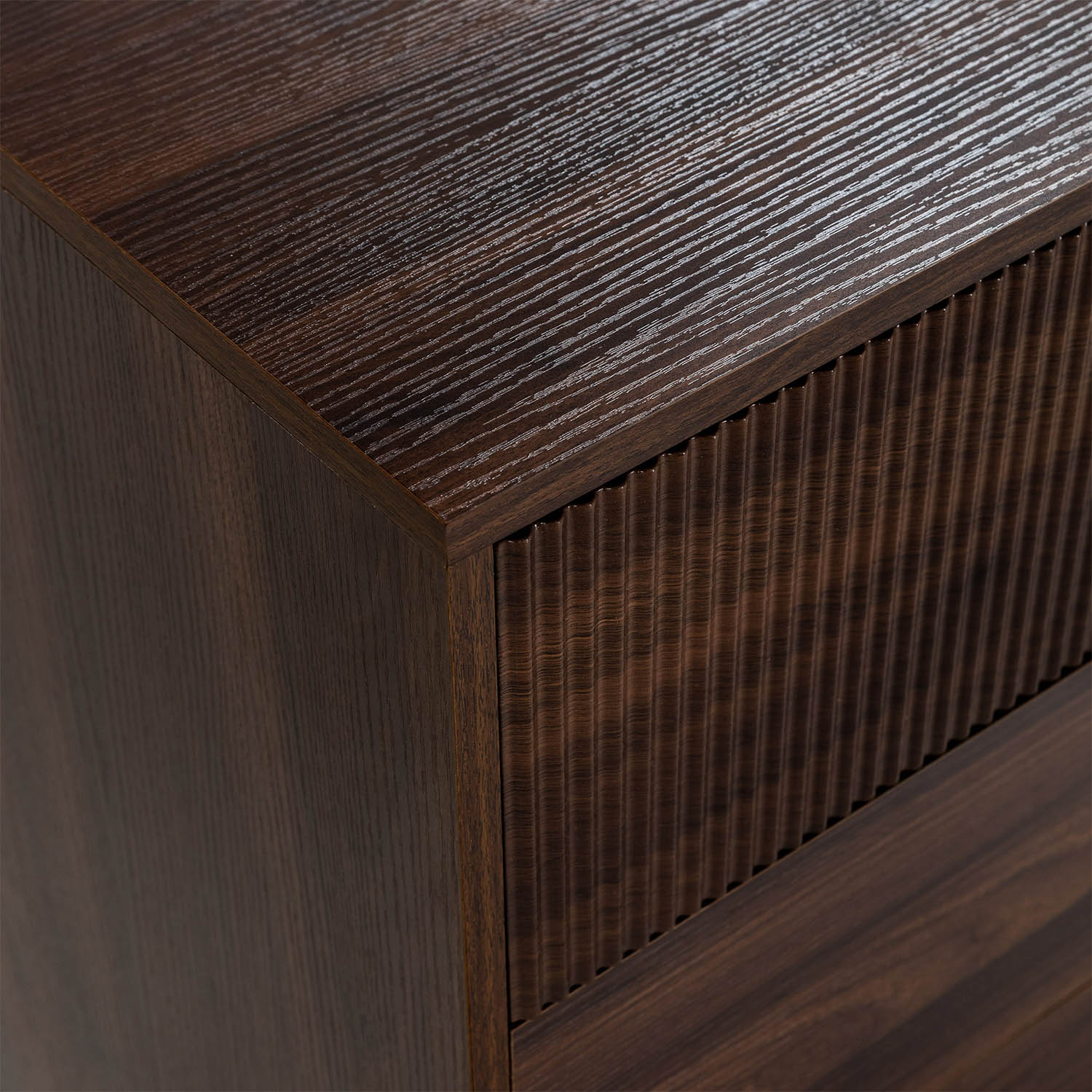 Armario de madera marrón oscuro con frente de cajón acanalado y superficie lisa.
