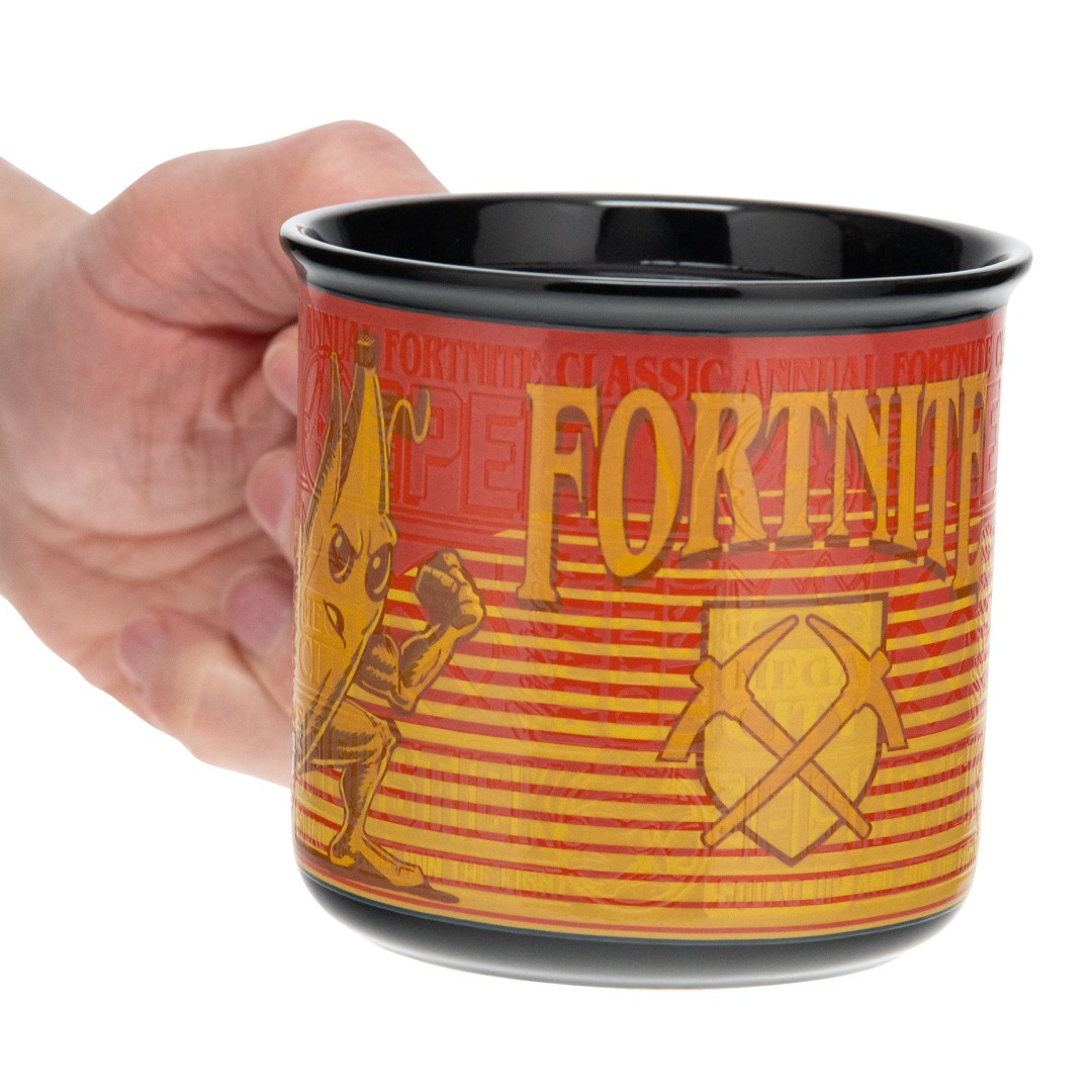 Ręka trzyma czerwono-żółty kubek Fortnite z postacią i kilofami.