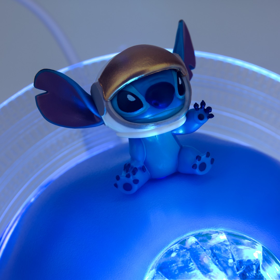 Niebieski Stitch w złotawej kasku pozdrawia z niebieskiej platformy.
