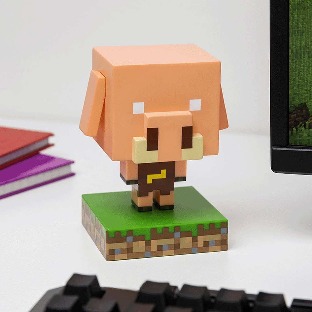 Figurka świni z Minecraft na trawiastym podłożu siedzi na biurku.