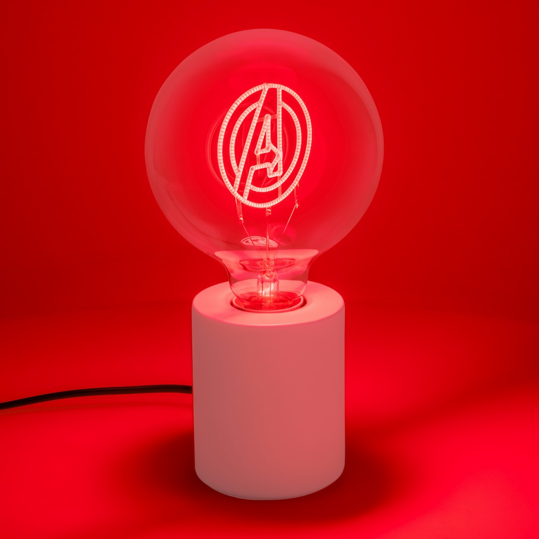 Przezroczysta żarówka z logo Avengers na różowej podstawie na czerwonym tle.
