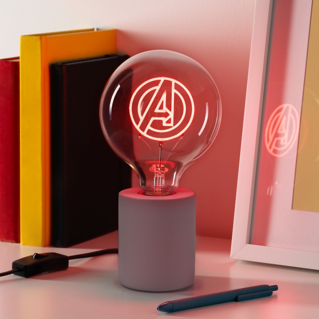 Lampa z logo Avengers świeci na czerwono na biurku obok książek.