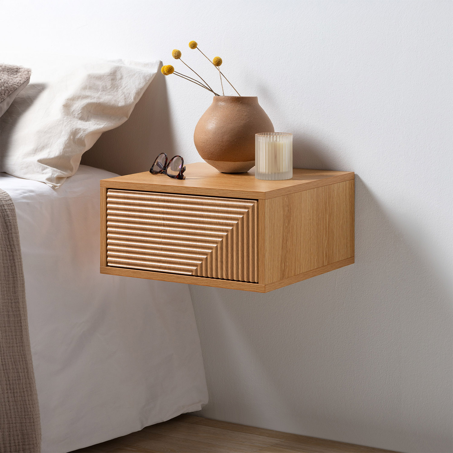 Una mesita de noche de madera con un cajón junto a una cama.