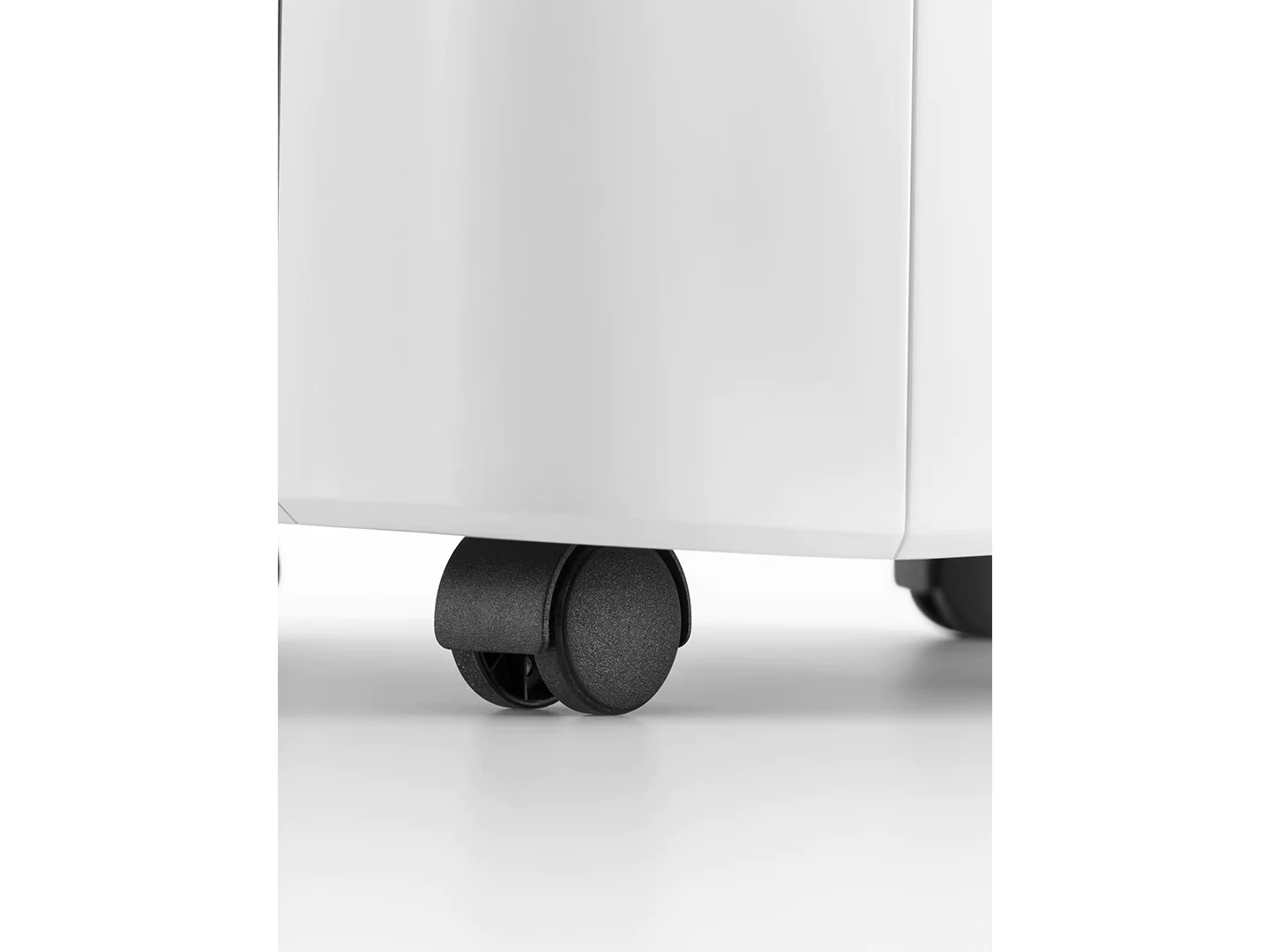 Primo piano di rotelle nere su un mobile bianco su sfondo bianco.