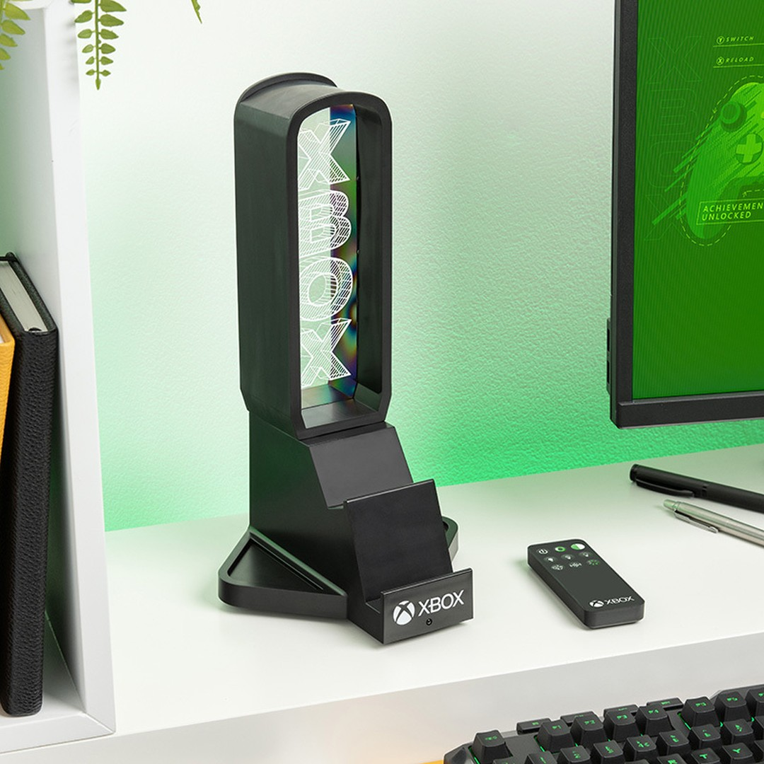 Czarny podświetlany stojak Xbox z logo Xbox na biurku obok monitora.