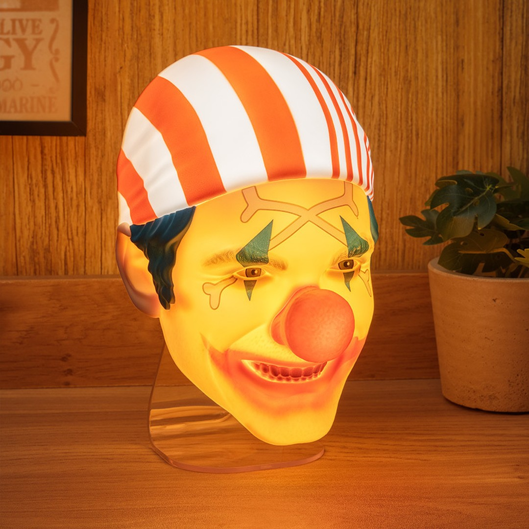 Świecąca lampa w kształcie głowy klauna z pomarańczowo-białymi paskami.