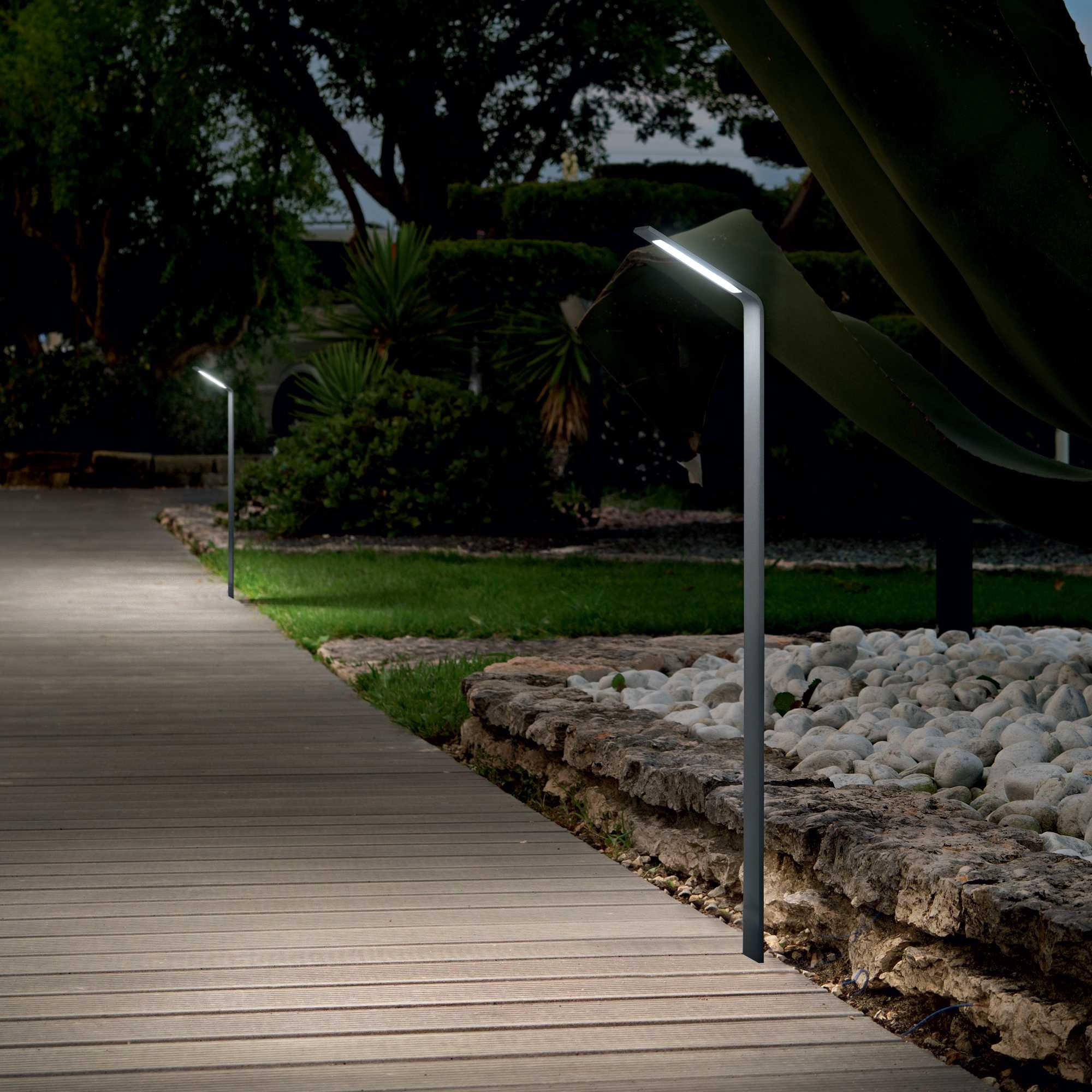 Un sentiero di assi di legno attraversa un giardino con illuminazione moderna.