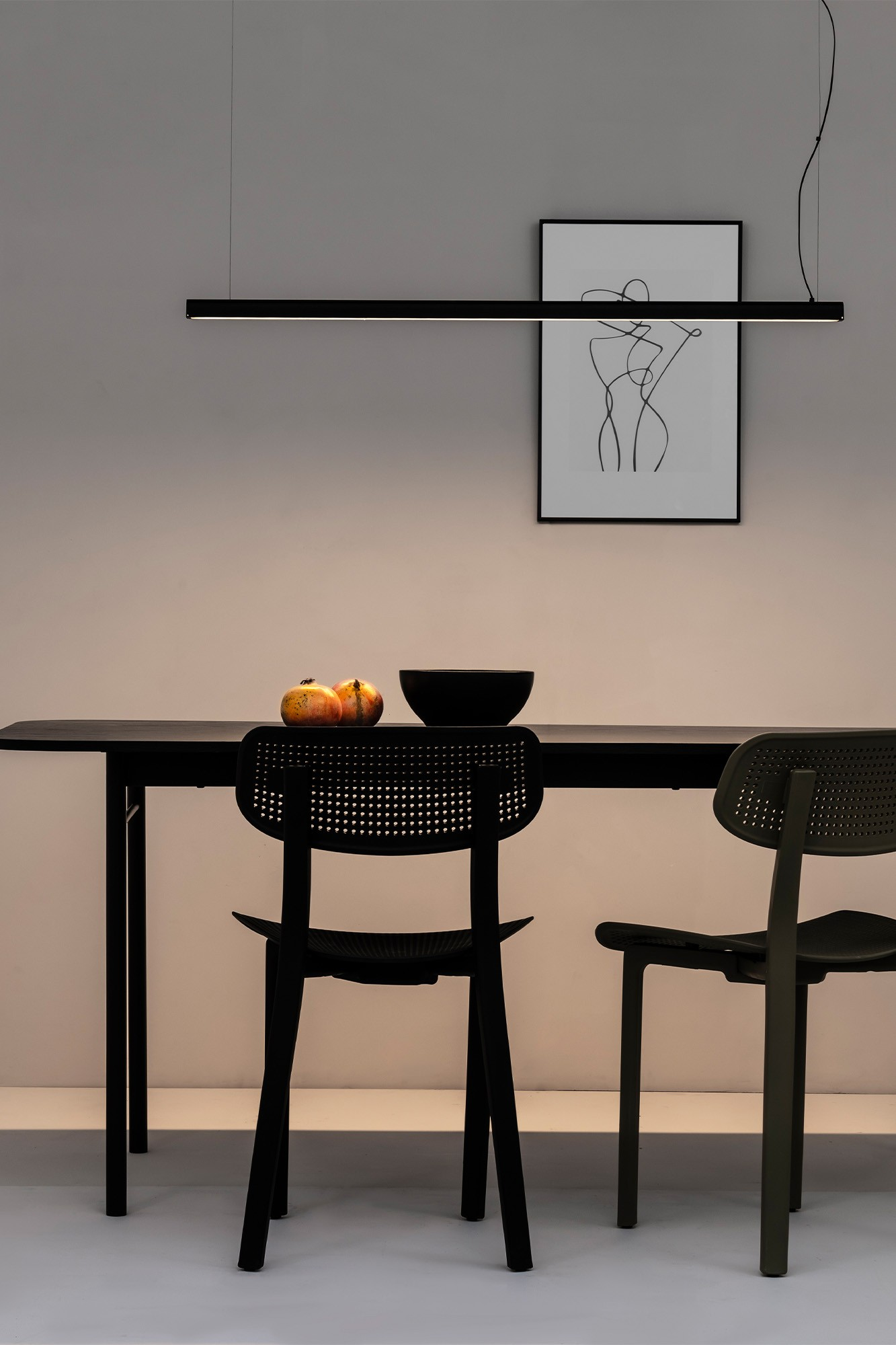 Un tavolo nero con due sedie, frutta e una lampada.