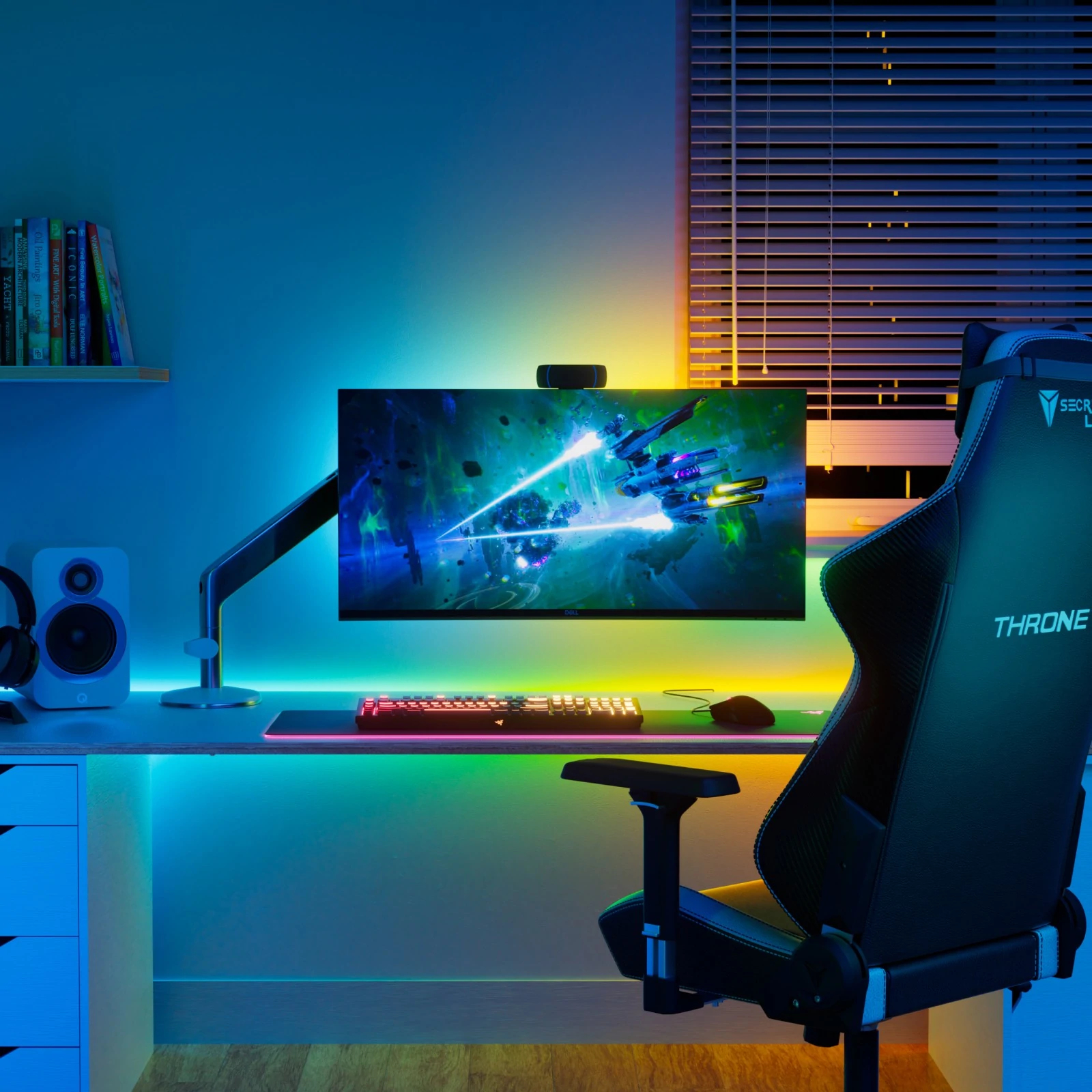 Ein Gaming-Setup mit beleuchtetem Schreibtisch, einem Monitor mit Weltraumspiel, Tastatur und Stuhl.