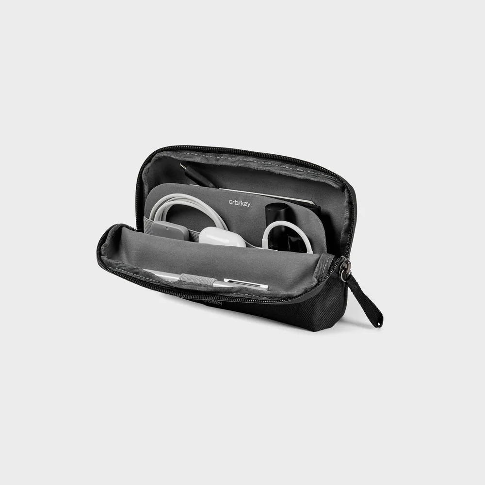 Czarna torba organizera Orbitkey z długopisami, słuchawkami, kablami i małym urządzeniem.