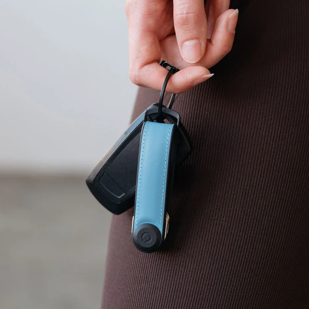 Una mano tiene chiavi dell'auto con un organizer per chiavi azzurro.