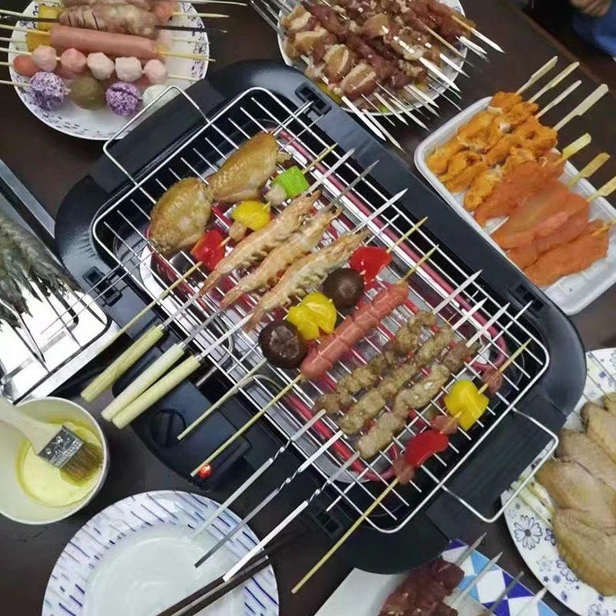 Una parrilla eléctrica con muchas brochetas de carne, camarones y verduras.