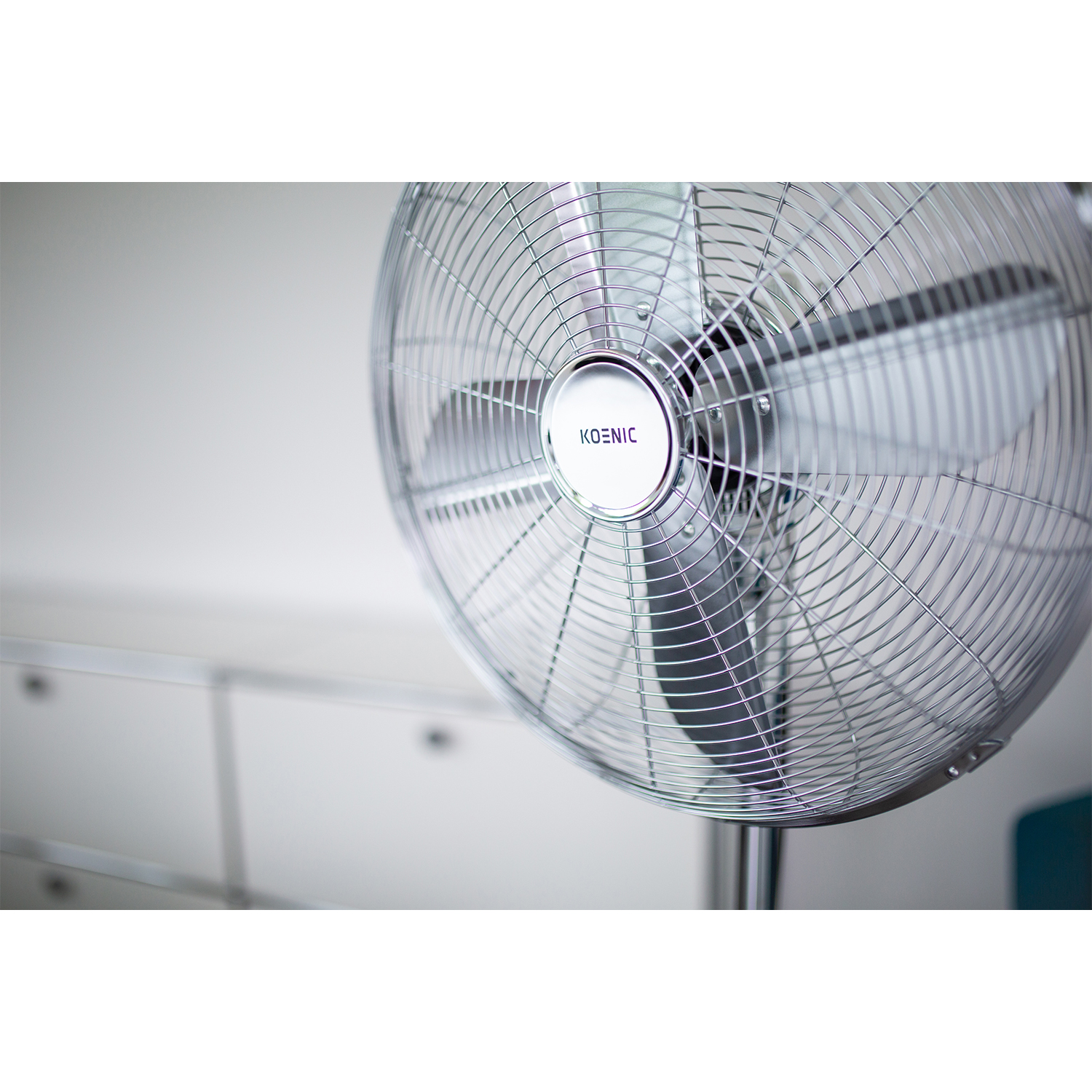Ein silberner Standventilator mit sich drehenden Blättern, nahaufnahme.