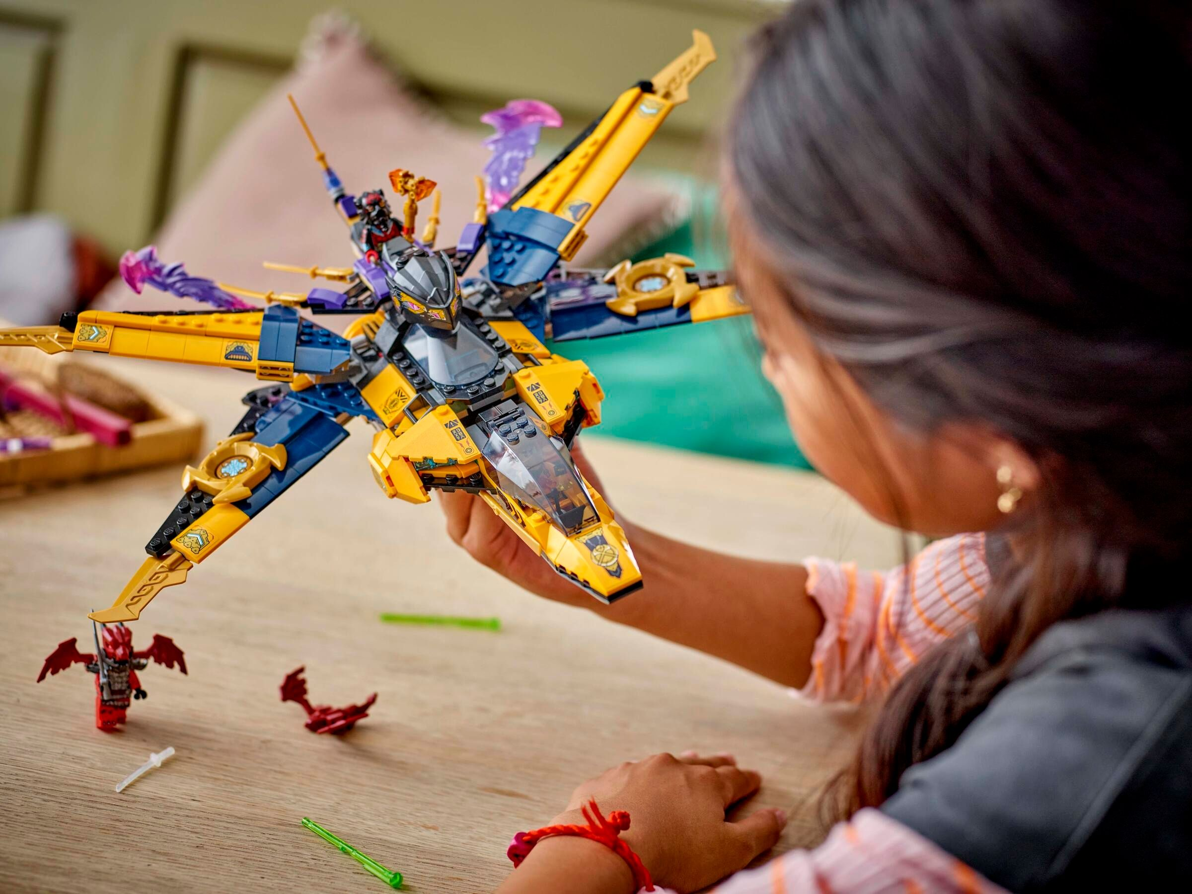 Ein Kind spielt mit einem gelben und blauen Lego-Raumschiff mit Figuren.