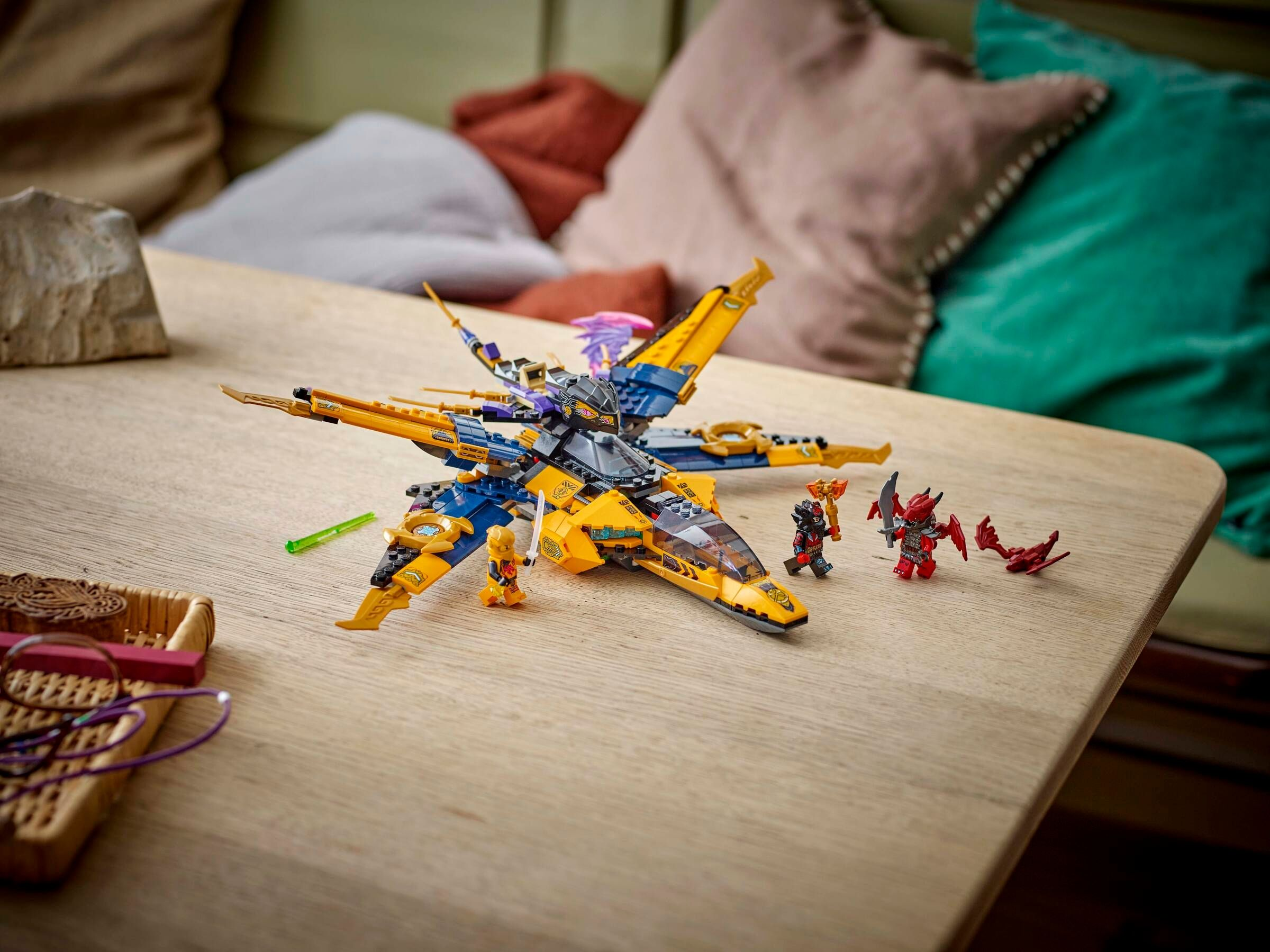 Ein gelb-blaues Lego-Raumschiff mit Figuren auf einem Holztisch.