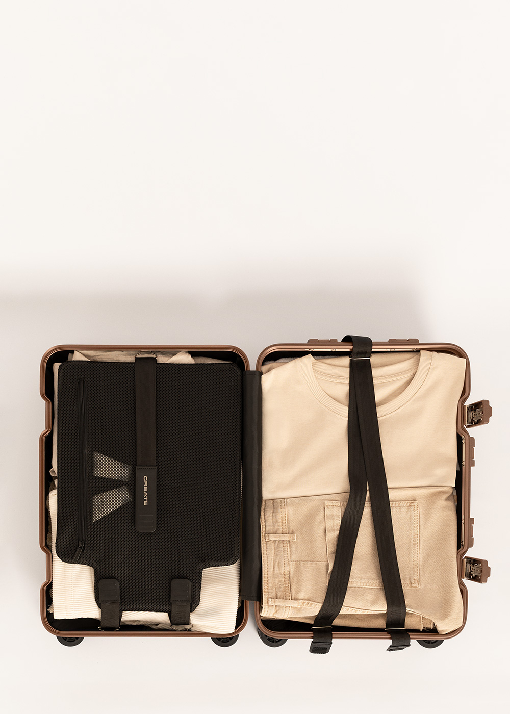 Maleta abierta con ropa: camiseta beige, pantalones, ropa blanca, bolsa de malla negra.