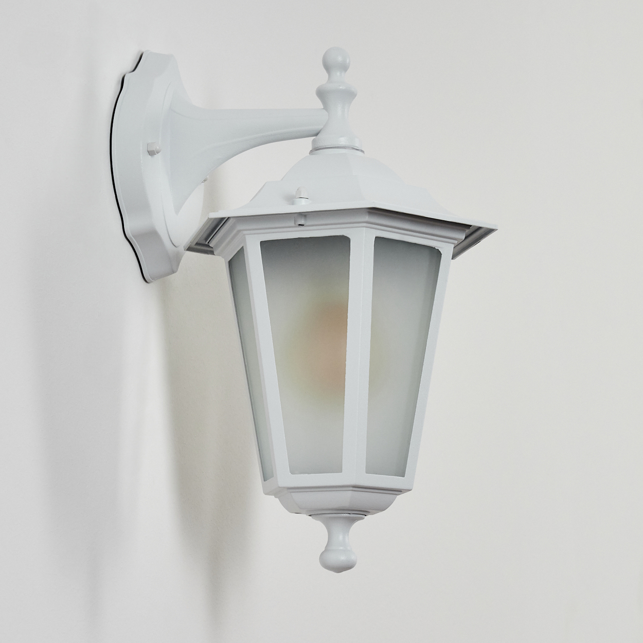Eine weiße Wandlampe mit mattem Glas und einem dekorativen Aufsatz.