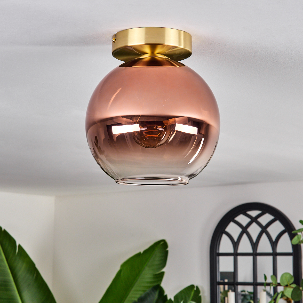 Moderne Deckenleuchte mit kugelförmigem, roségoldenem Schirm und Messingbasis.