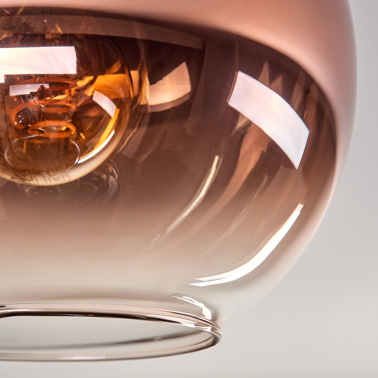 Eine kupferfarbene Lampe mit einem bernsteinfarbenen Glaskolben und einer Glühbirne.