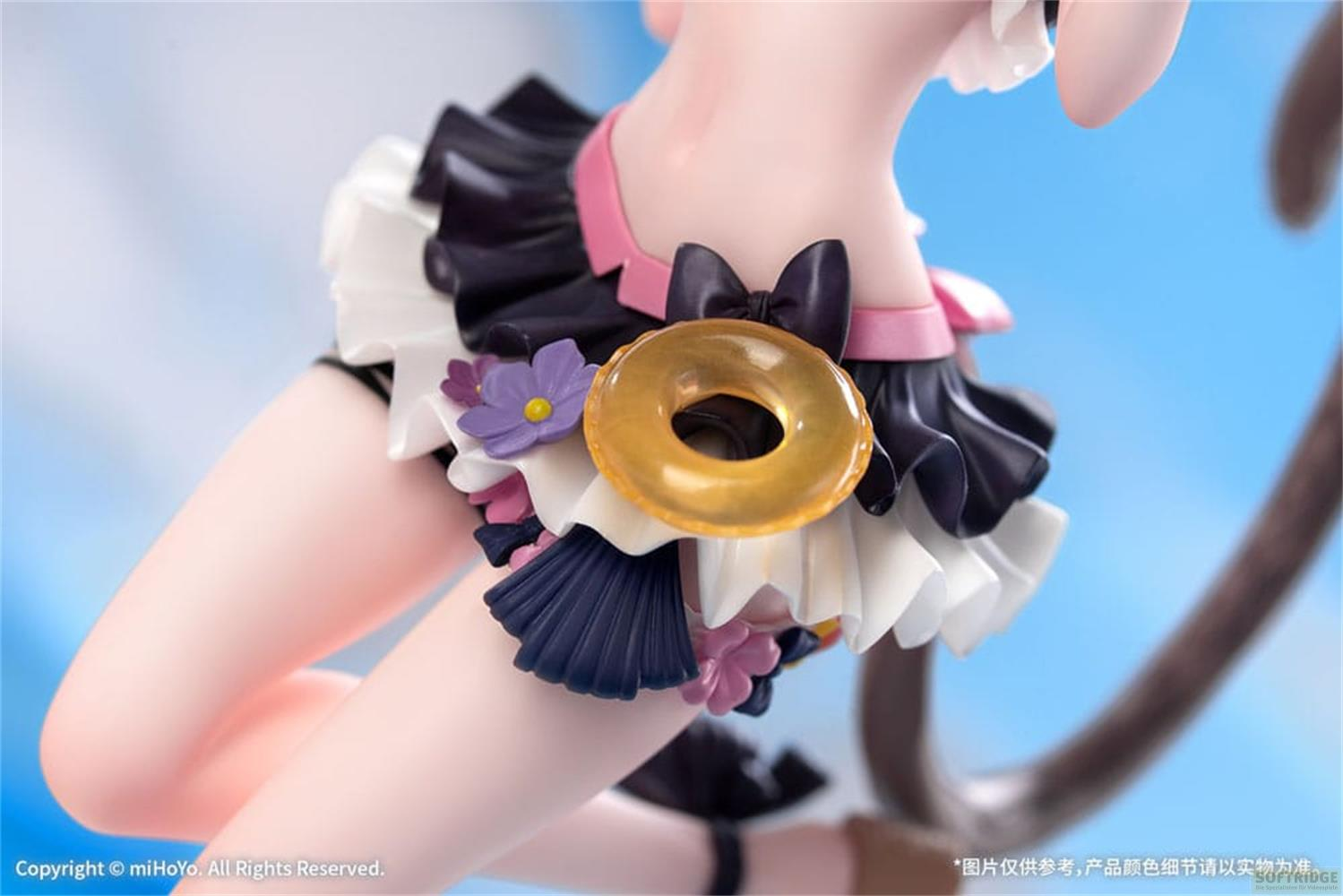 Eine Figur mit einem rüschenartigen Rock, einer goldenen Donut-Dekoration und Blumen.