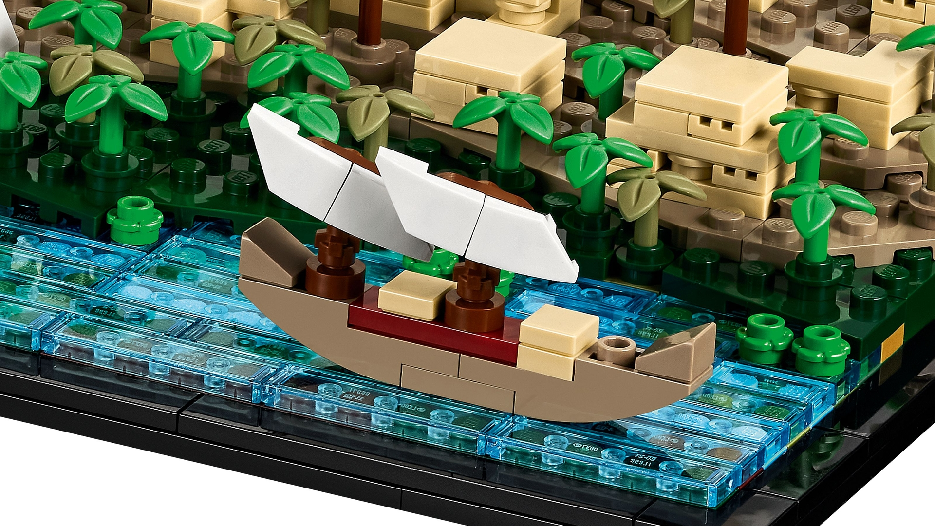 Ein Lego-Segelboot mit weißen Segeln auf blauem Wasser vor einer Dschungelkulisse.