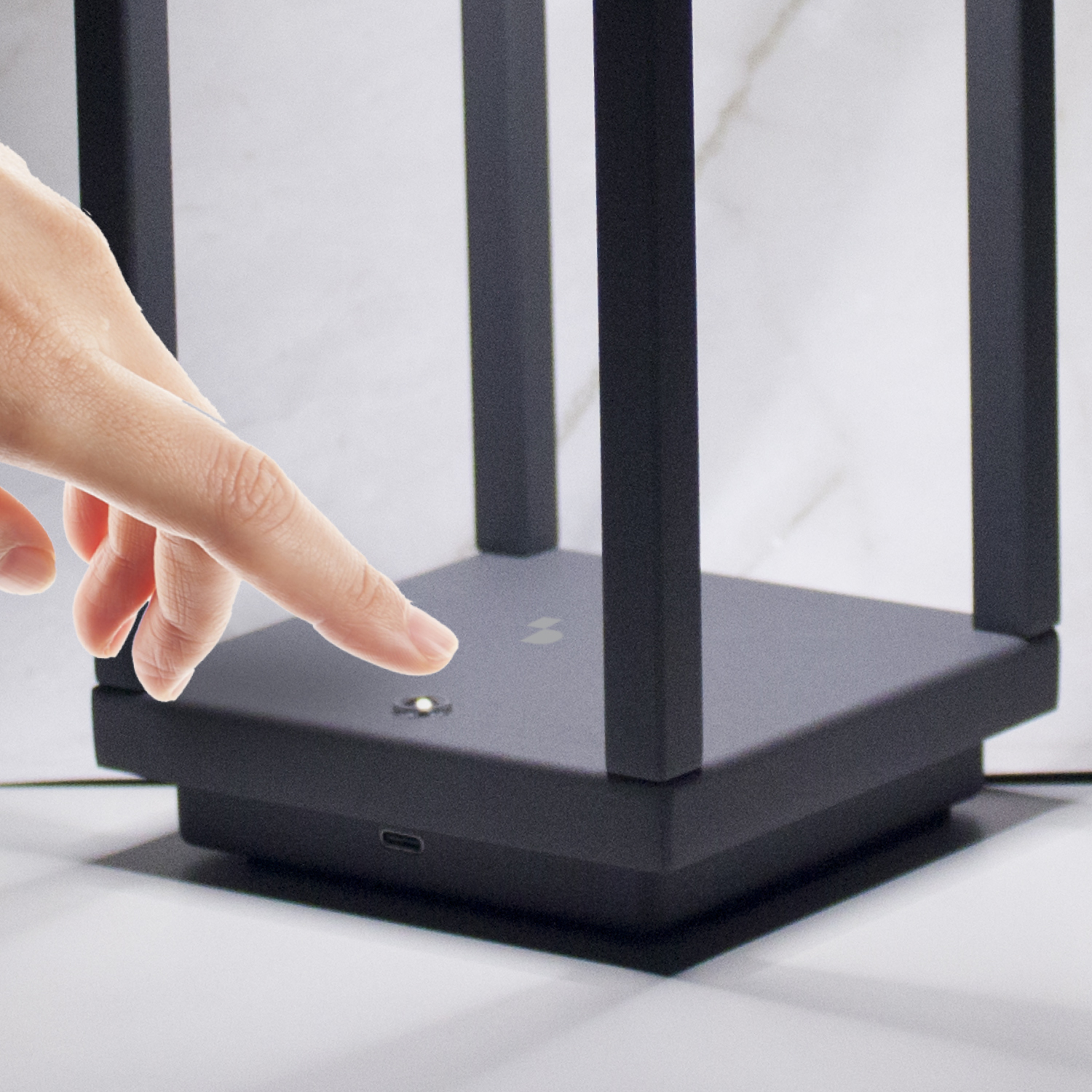 Una mano tocca un router nero con antenne. Una luce è illuminata.