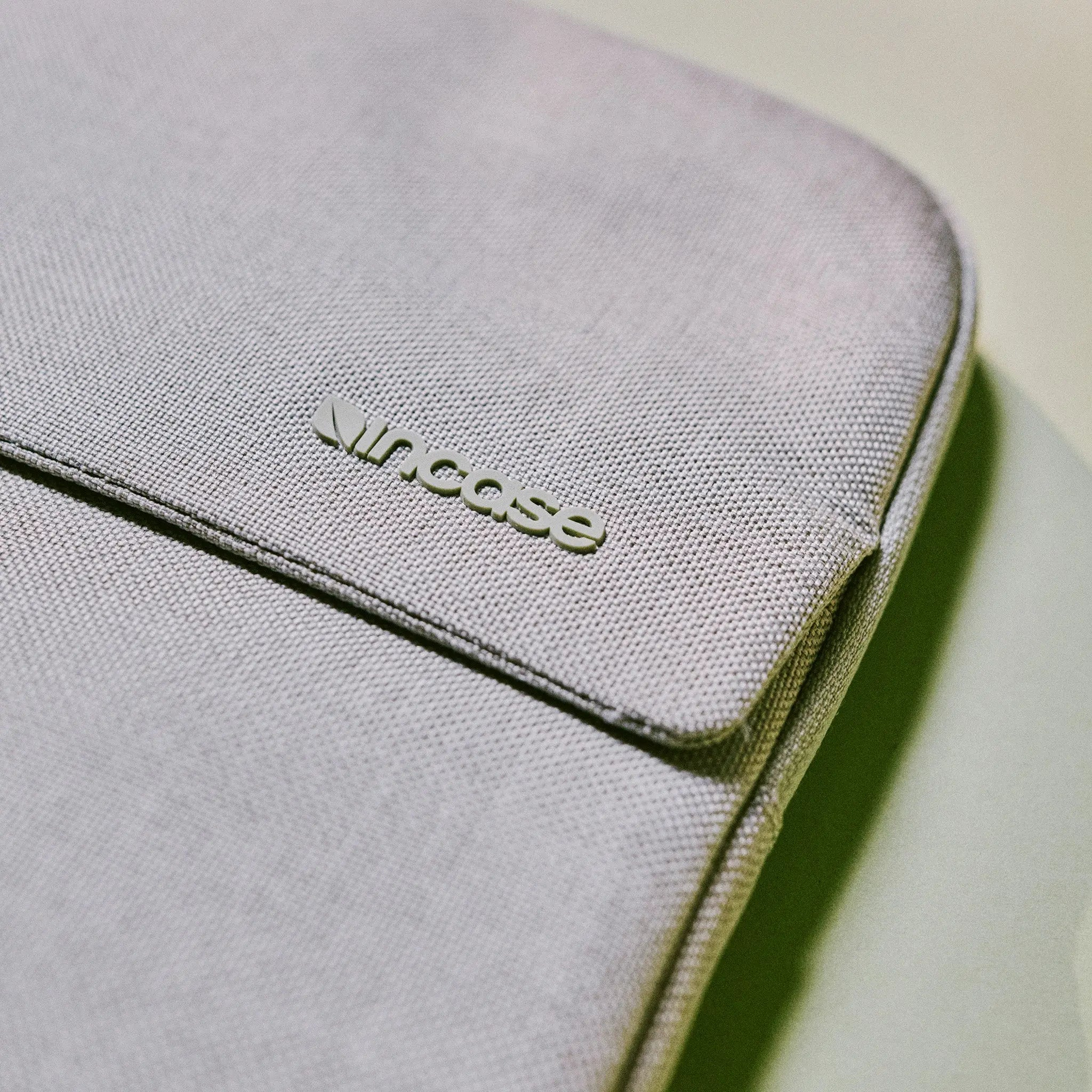Borsa in tessuto grigio con logo in rilievo, dettaglio ravvicinato.