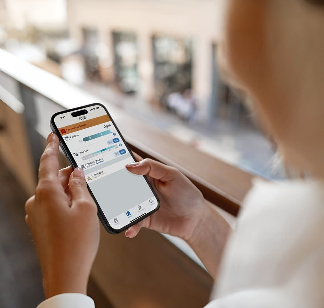 Eine Person hält ein Smartphone, das die Eve App zeigt. Es gibt Einstellungen für Position, Zeitplan und Automatisierung.