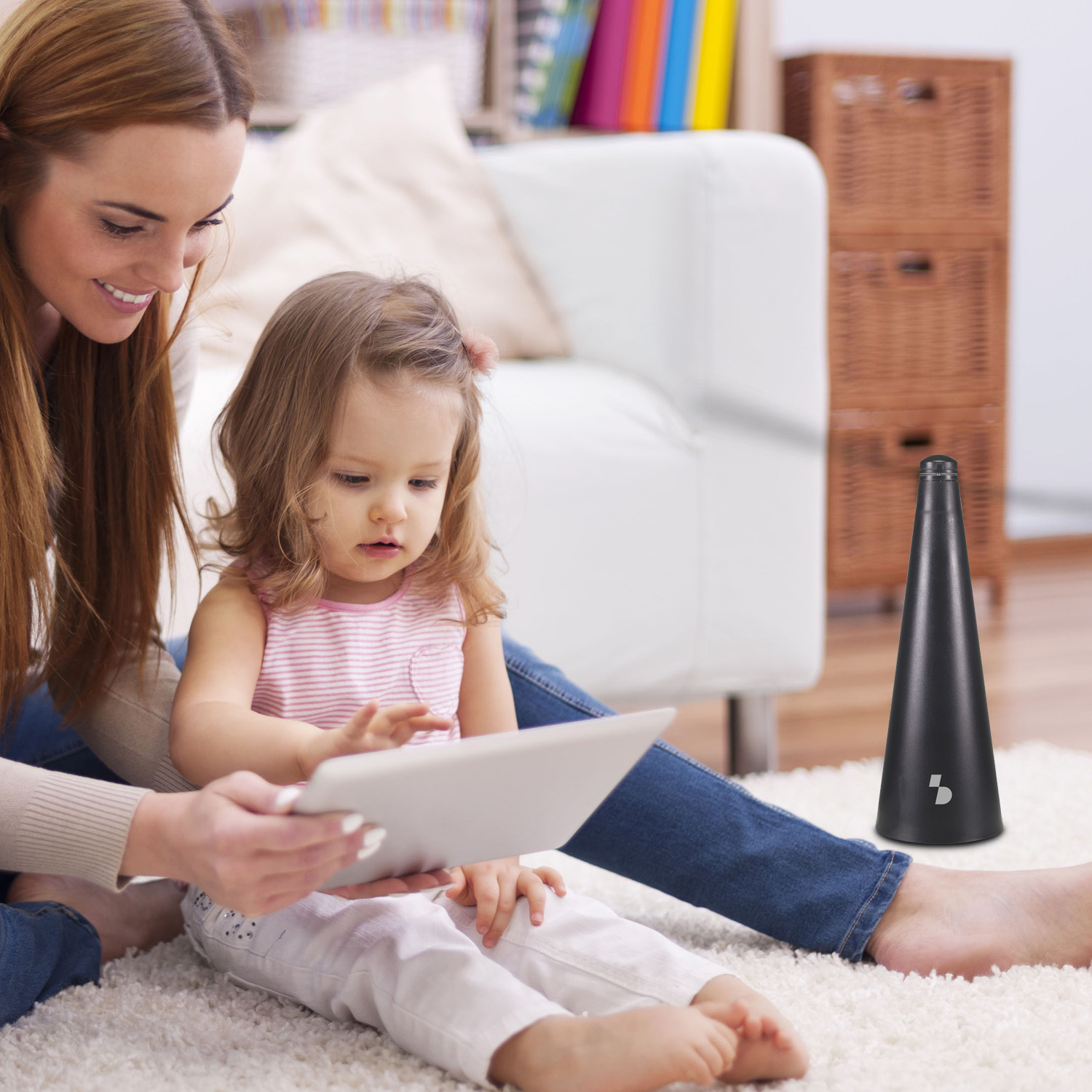 Madre e figlia sedute sul tappeto guardano un tablet insieme.