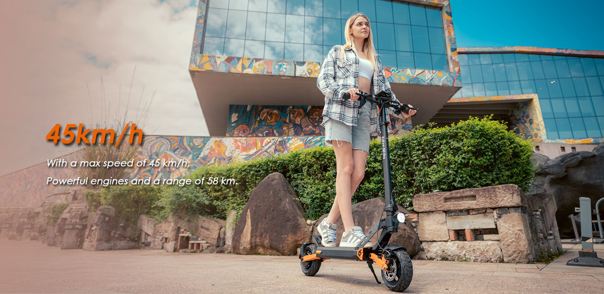 Una donna è in piedi su uno scooter elettrico davanti a un edificio con mosaici colorati.