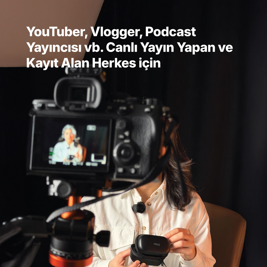 Bir kişi tripod üzerine monte edilmiş bir kameranın önünde siyah bir kılıf tutuyor.