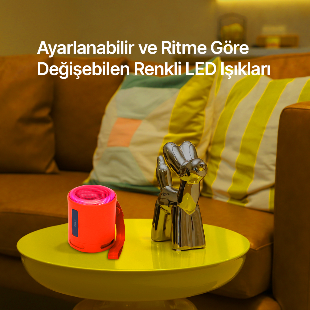 Turuncu hoparlör ve gümüş köpek heykel sarı masada.