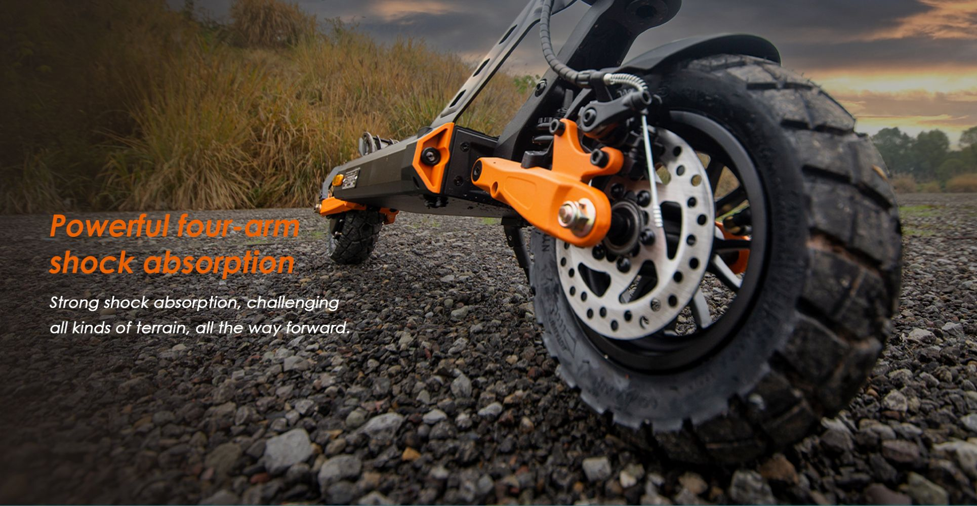 Uno scooter elettrico con pneumatici larghi e ammortizzatori arancioni sulla ghiaia.