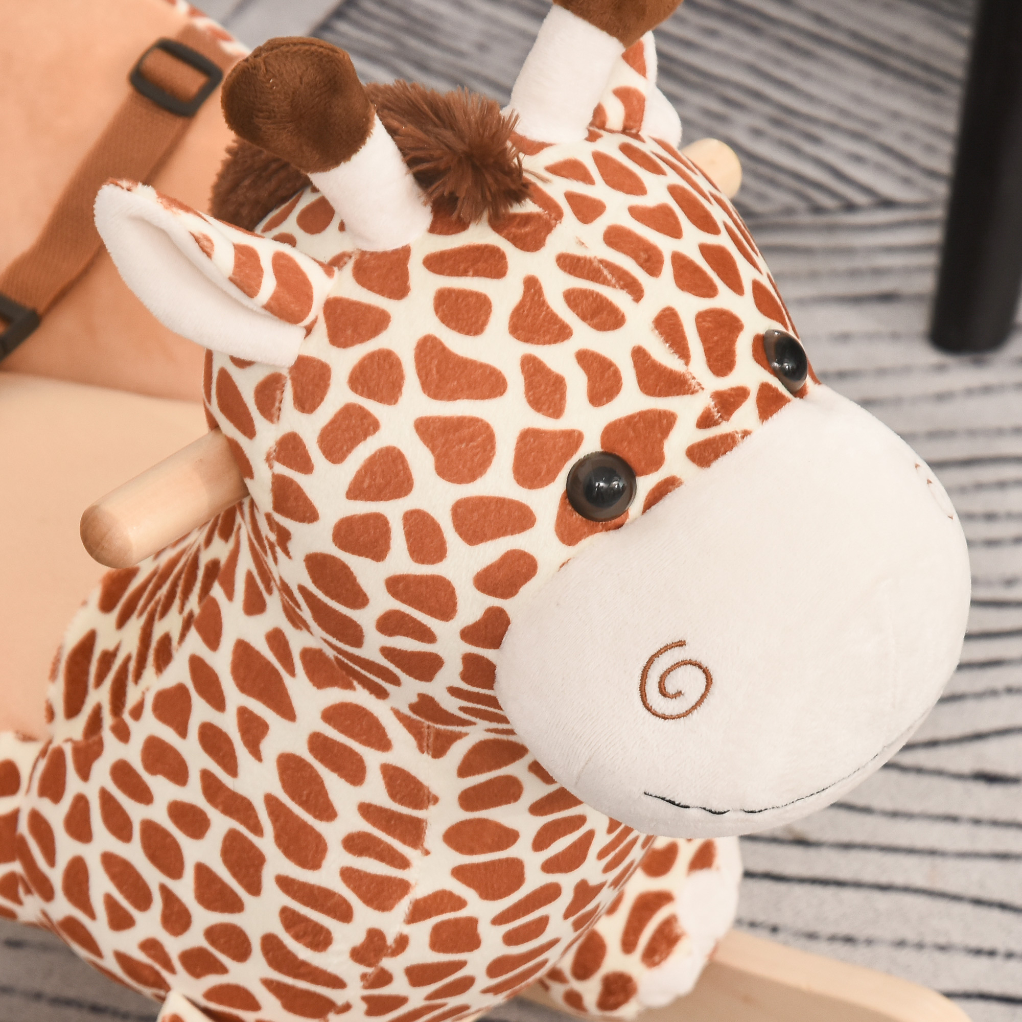 Un peluche de jirafa con manchas marrones sobre fondo claro.