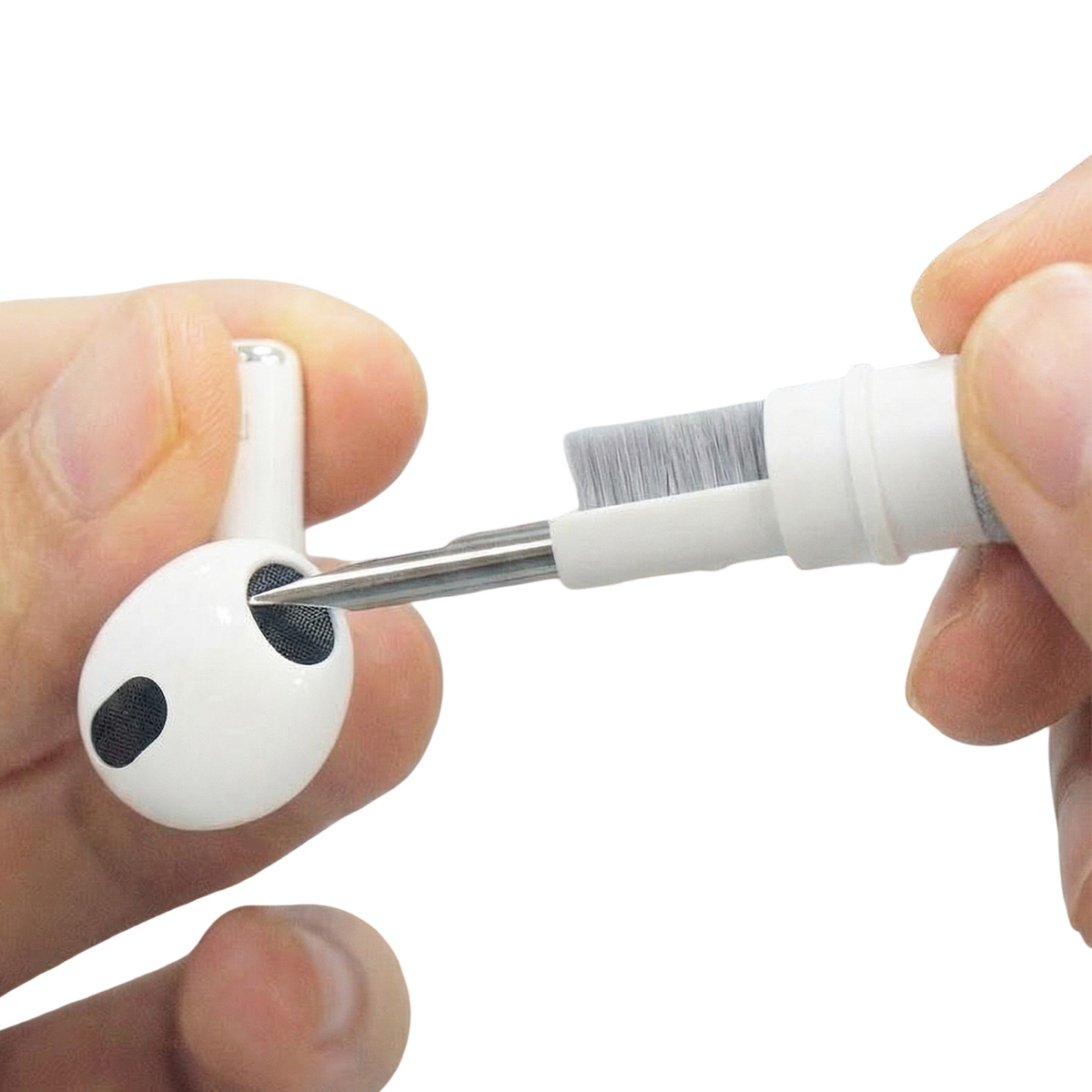 Una mano tiene un auricolare bianco mentre un'altra mano tiene uno strumento di pulizia con punta in metallo e spazzola.