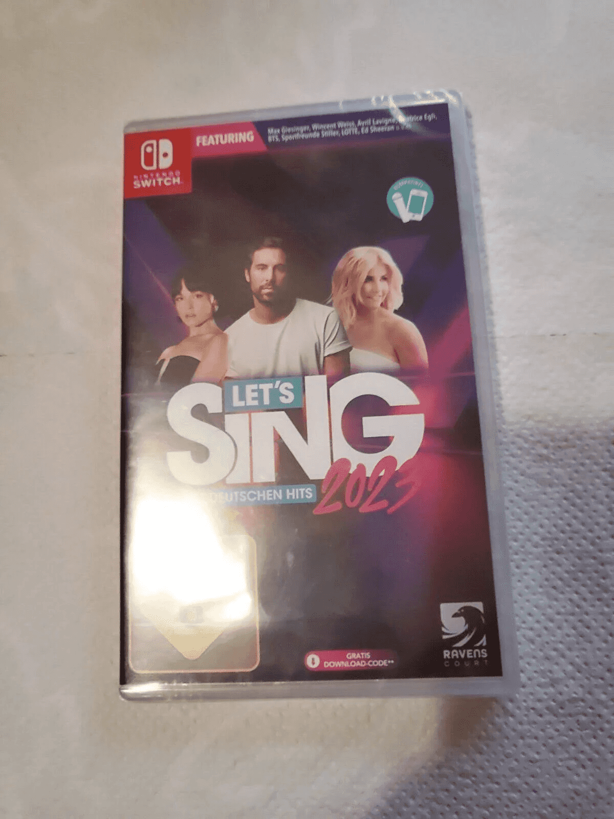 Cover des Nintendo Switch Spiels 'Let's Sing 2023' mit drei Sängern und dem Logo.