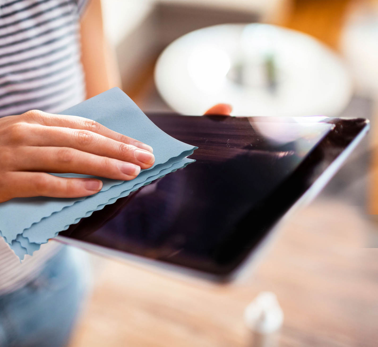 Una persona pulisce lo schermo di un tablet con un panno blu.