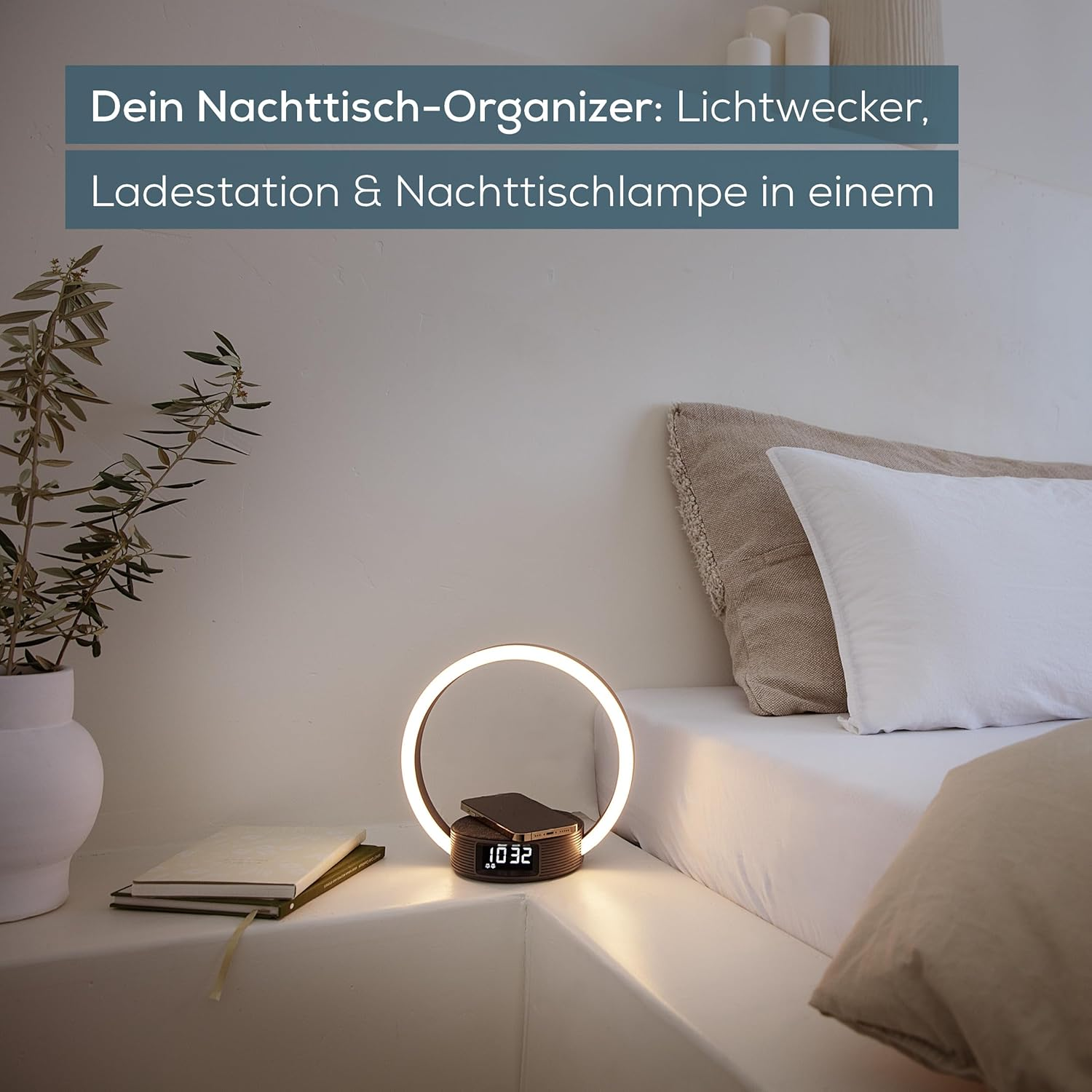 Ein Nachttisch mit Lampe, Ladestation, Uhr und Büchern.