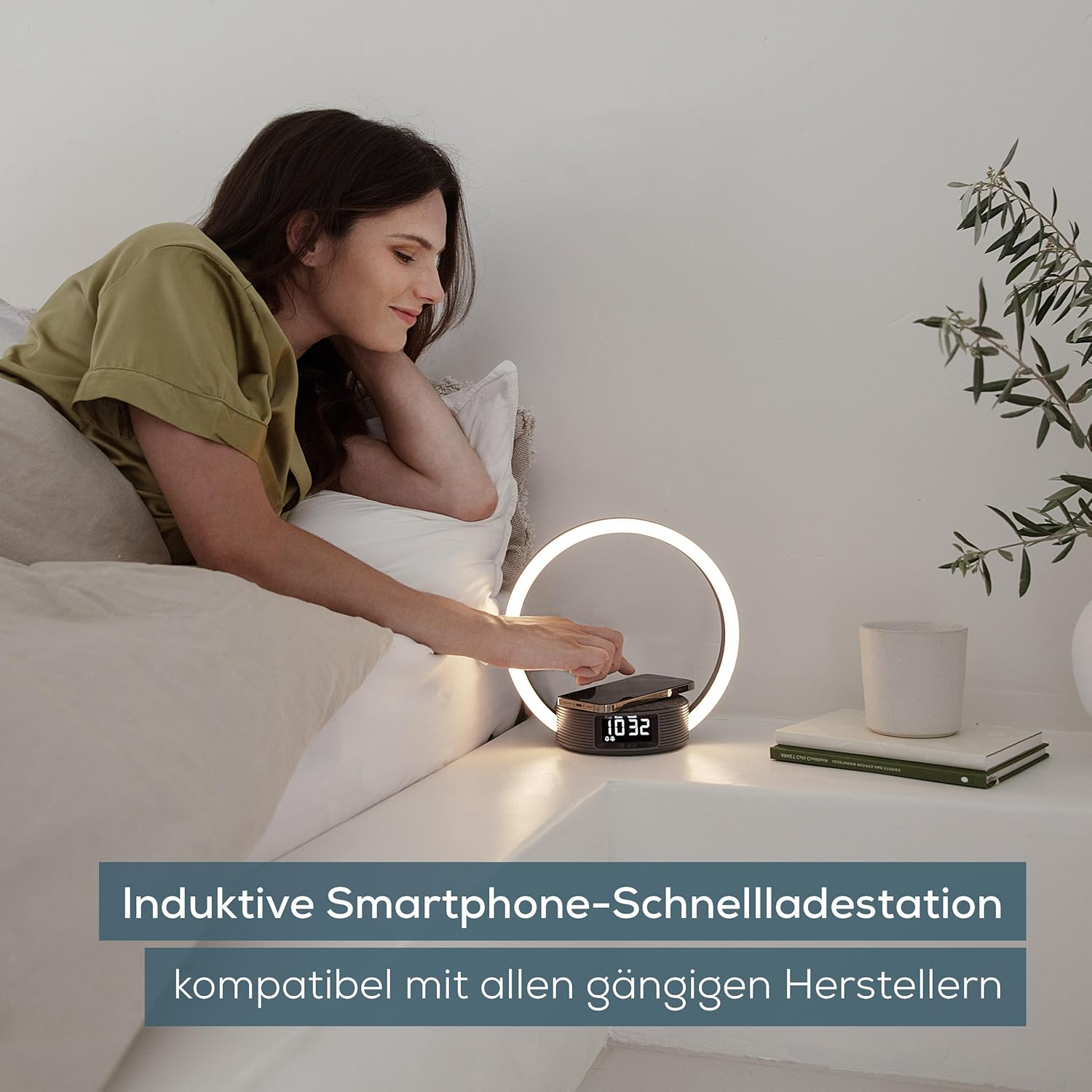 Frau liegt im Bett, legt ein Handy auf Ladestation mit Uhr.