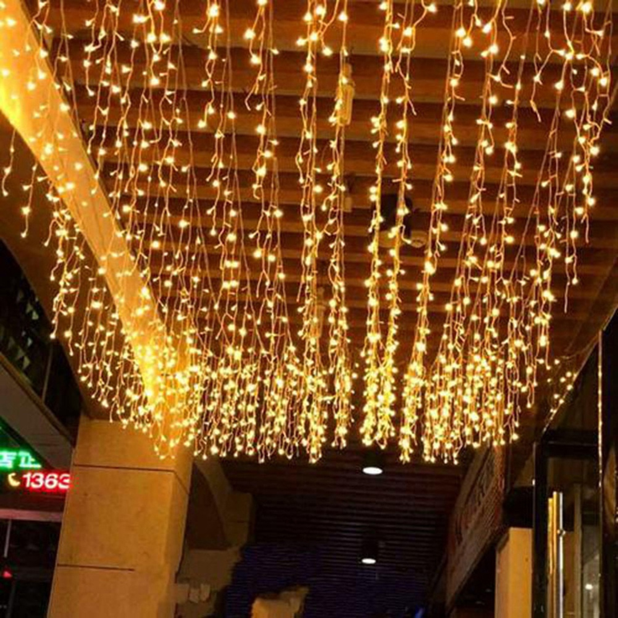 Viele bernsteinfarbene Lichterketten hängen von einer Holzdecke, die einen Durchgang beleuchten.